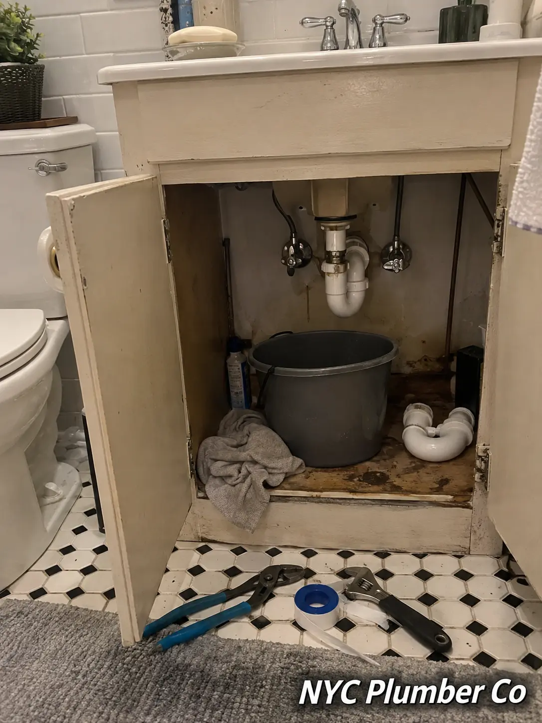 Leaking bathroom vanity drain being repaired under the sink