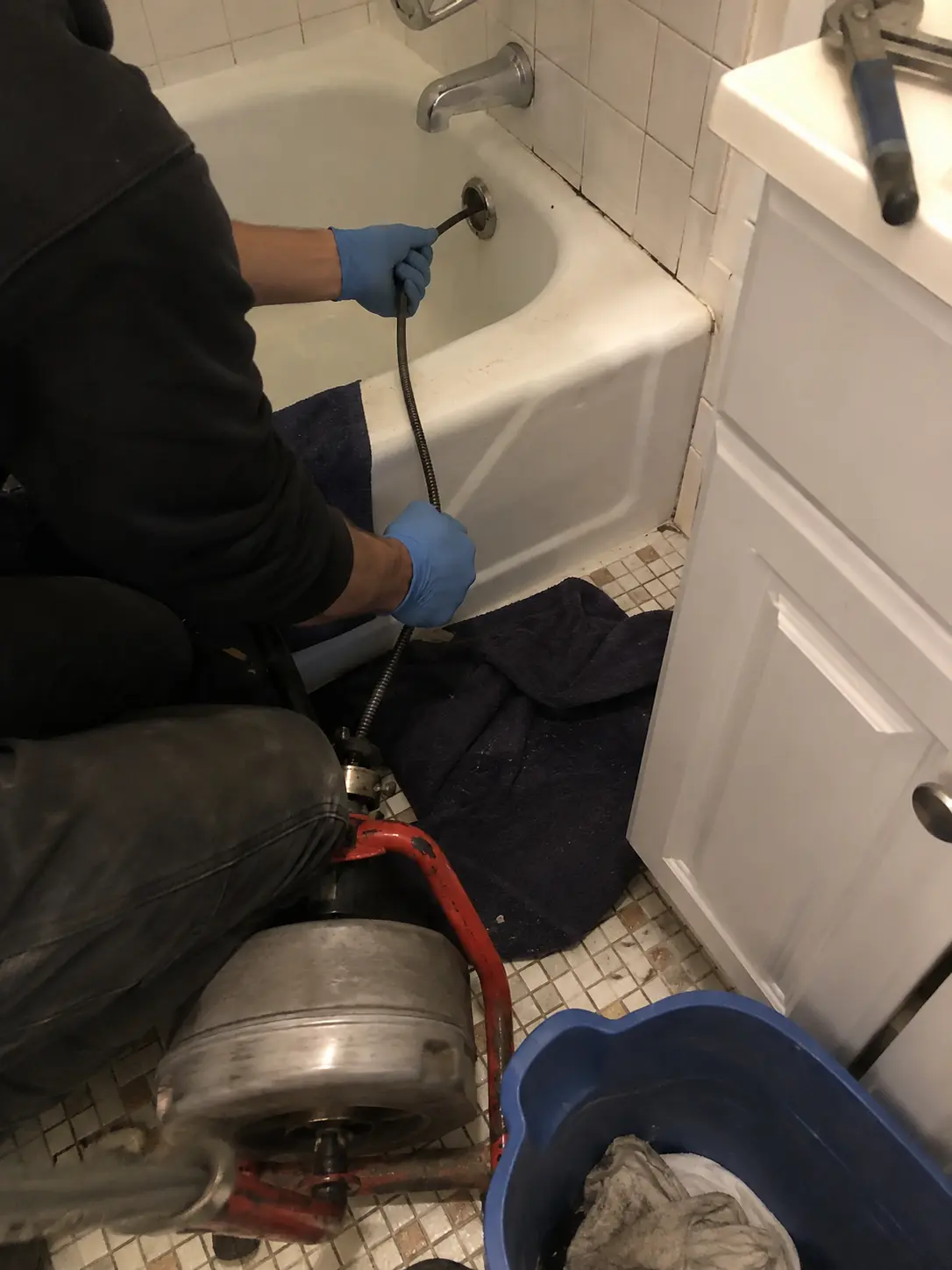 Plumber using a drain machine to clear a clogged bathtub drain