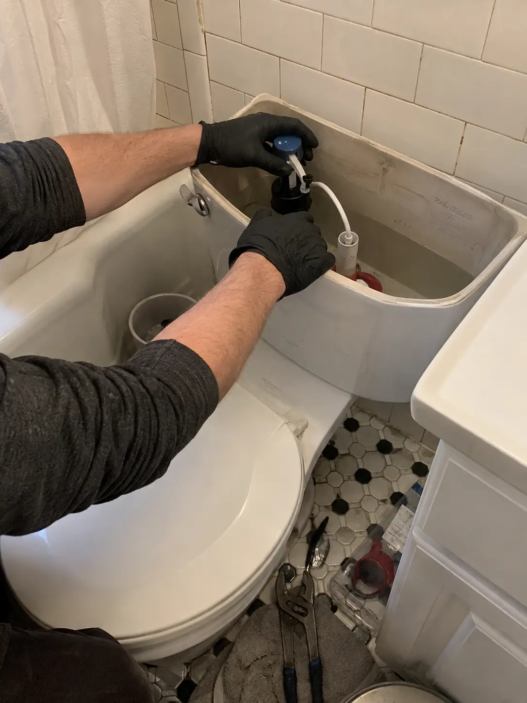 Plumber replacing the fill valve inside a toilet tank