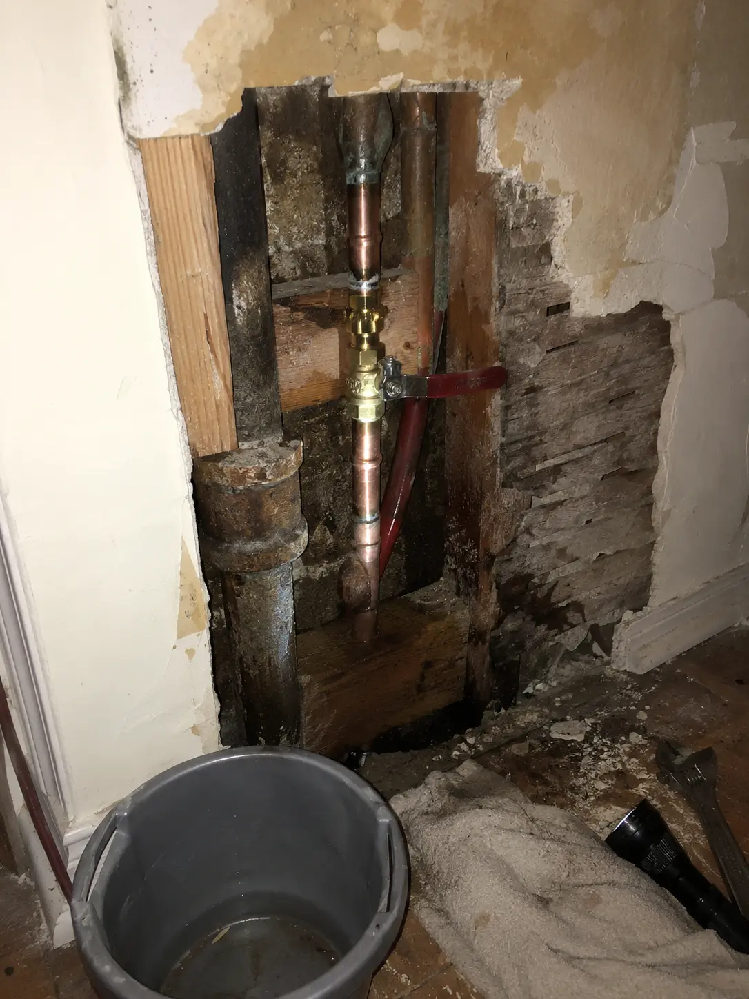 Open wall showing copper water piping and a shutoff valve during a leak repair